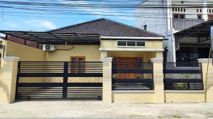 a yellow house with a fence in front of it at Zavira House Purwokerto in Purwokerto