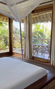 Schlafzimmer mit einem Bett und Blick auf eine Veranda in der Unterkunft Maisha Nungwi - Boutique Hotel in Nungwi
