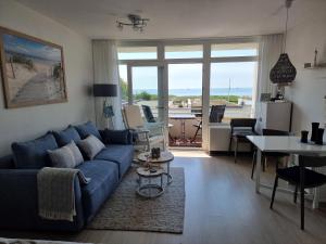 a living room with a blue couch and a table at Wohnung Südstrand Glück in Fehmarn