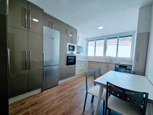 Una cocina con mesa y sillas y un refrigerador. en VV Milenaiver "by henrypole home", en Los Cancajos