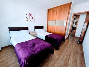 Dos camas en una habitación con sábanas moradas. en VV Milenaiver "by henrypole home", en Los Cancajos 36 fotos más