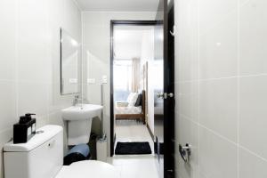 a white bathroom with a toilet and a sink at Cubao Manhattan Heights Residential Condo TC10N - Bright Studio with Pool, Balcony - Next to AliMall and SM - Walking Distance to Araneta Coliseum and Gateway Mall in Cubao Quezon City - Staycations by SMS in Manila +19 photos