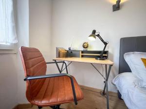 a desk with a lamp and a chair next to a bed at Meublé classé 3 étoiles Centre Ville de Céret in Céret
