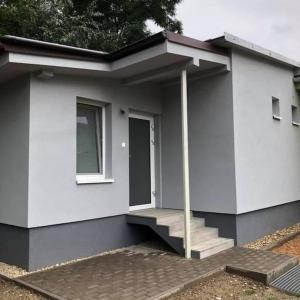 a small white house with stairs and a window at Apartmán u Slávky in Ploské