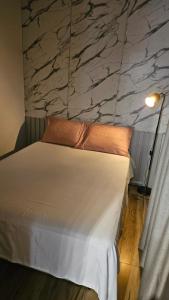 a bedroom with a white bed with a stone wall at Casa Contêiner Luxo in Foz do Iguaçu