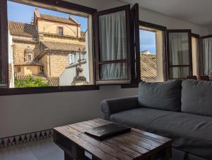 un soggiorno con divano, tavolo e finestre di Apartamentos Plaza a Cordoba