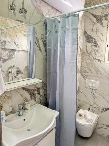 a bathroom with a sink and a toilet and a mirror at Rose Apartament Sarande in Çukë +10 photos
