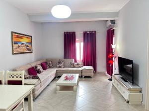 a living room with a couch and a tv at Rose Apartament Sarande in Çukë
