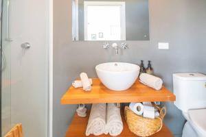 a bathroom with a sink on a wooden shelf at Raglan Studio at The Coastal Retreat in Raglan +23 photos