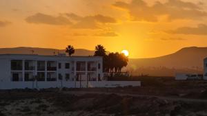 a house with the sunset in the background at Casa Fin del Mundo El Cotillo in Cotillo