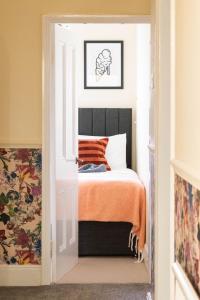 a bedroom with a bed with an orange blanket at The Parade -Corner Plot Getaways in Redcar