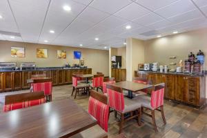 a restaurant with wooden tables and red chairs at Comfort Suites At the University in Conway