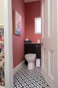 a bathroom with a toilet and a pink wall at The Parade -Corner Plot Getaways in Redcar