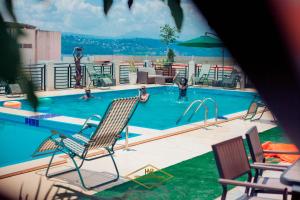 einen Pool mit Stühlen und Menschen im Wasser in der Unterkunft Hotel New Riviera bukavu in Bukavu