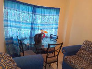 a dining room table with chairs and a blue curtain at Lovely 1-Bed Cottage in St catherine Jamaica in Ewarton