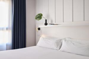 una camera da letto con un letto con lenzuola bianche e una pianta di Ramirez Flats Valencia a Valencia