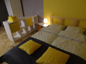 2 łóżka z żółtymi poduszkami w sypialni w obiekcie Apartamenty Polna w Kaliszu