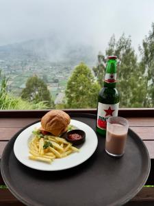 a plate with a sandwich and fries and a bottle of drink at Pinggan luxury camp in Baturaja