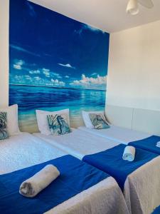 two beds in a room with a painting of the ocean at Apartamento vista mar Atalaia todos quartos climatizados in Aracaju
