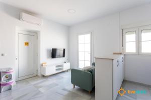 a white living room with a couch and a tv at Torre Argantonio by LiveWork in Cádiz