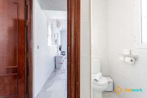a white bathroom with a toilet and a sink at Torre Argantonio by LiveWork in Cádiz +19 photos