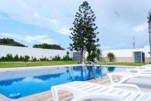 a swimming pool with white chairs and a tree at Villa de Luxe à Casablanca Piscine Privée Fibre 100 Mbps Netflix et YouTube Premium in Casablanca