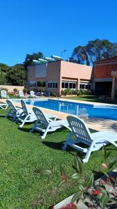 a row of lawn chairs next to a swimming pool at Hotel del Rio - La Cruz Corrientes in La Cruz