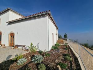 a white building with a fence next to a garden at Quinta da Chumbaria - heaven on a hilltop, peace and stunning views! in Casal do Monte
