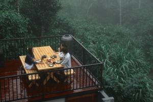 Deux personnes assises à une table en bois sur un balcon dans l'établissement Bhadra - The Estate Villa, à Wayanad