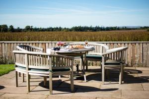 a table with three chairs and a table with a glass of wine at Border View Cottage in Duddo