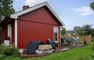 une grange rouge avec des chaises et une table sur une terrasse dans l'établissement Lovely Home In Vänersnäs, à Hallby 14 autres photos