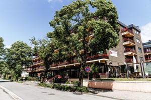 a building with a tree in front of a street at Haus Vier Jahreszeiten am See Apartment am Kranichsee in Hahnenklee-Bockswiese