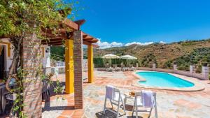 patio z basenem i krzesłami obok domu w obiekcie Casa Torre del Manzano Torrox by Ruralidays w mieście Torrox
