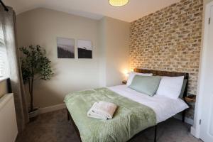 a bedroom with a bed with a brick wall at 'Station House' Cosy Renovated Family-Friendly Home in Runcorn, Cheshire - Train Station Liverpool Chester Links, Brindley Theatre in Runcorn