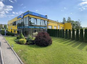 AizkraukleAvēnija的一栋黄色建筑位于一栋建筑前的草坪上