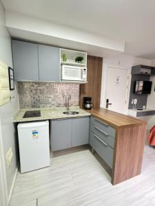 una pequeña cocina con nevera blanca y fregadero en Estudio Executivo com Wi-Fi Cozinha e Metro Centro SP, en São Paulo