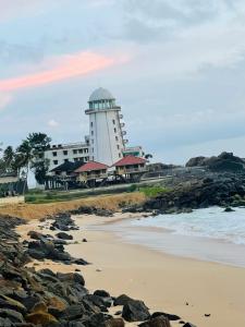 a lighthouse on the shore of a rocky beach at Blue Maalu Resort in Ambalangoda
