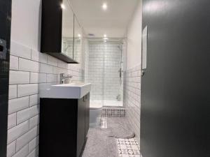 un bagno bianco con lavandino e doccia di Cool warehouse conversion apt in Chiswick London a Londra Altre 4 foto