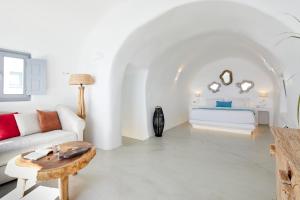 Una sala de estar blanca con un sofá y una mesa. en Imerovigli Iliovasilema Villa, en Imerovigli