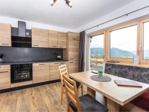 uma cozinha com uma mesa de madeira e algumas janelas em Apartment Gletscherblick by Interhome em Zell am See mais 33 fotografias