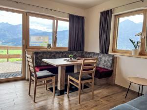 uma sala de jantar com mesa, cadeiras e janelas em Apartment Gletscherblick by Interhome em Zell am See