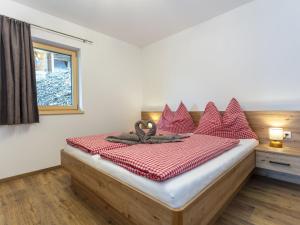 um quarto com uma cama com almofadas vermelhas e uma janela em Apartment Gletscherblick by Interhome em Zell am See
