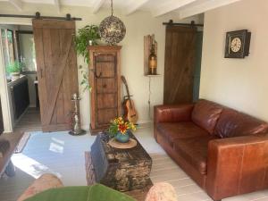 sala de estar con sofá de cuero y guitarra en Het Zalige Buitenleven, en Lanaken