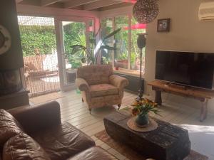 Una sala de estar con un sofá, una silla y un televisor. en Het Zalige Buitenleven, en Lanaken