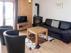 a living room with a black couch and a table at Chalet Fuchsia by Interhome in Les Collons +11 photos