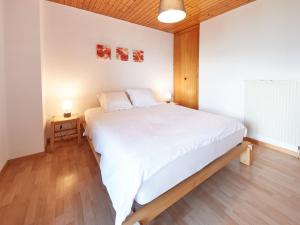 a bedroom with a large white bed and two lamps at Chalet Fuchsia by Interhome in Les Collons