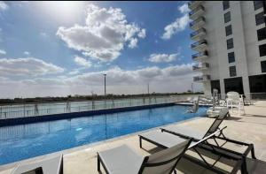 a swimming pool on the roof of a building at F1 - Daisy Hill 1BR Waters Edge Canal View Yas island - Theme Parks in Abu Dhabi