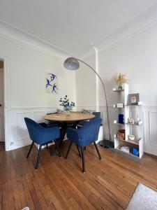 a dining room with a table and blue chairs at Appartement Cosy et agréable in Colombes