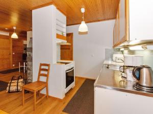 a kitchen with white cabinets and a table and a chair at Holiday Home Kulta-käkönen 10 by bomba by Interhome in Nurmes