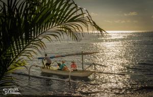 a group of people sitting in a boat on the water at Santai Hotel in Amed